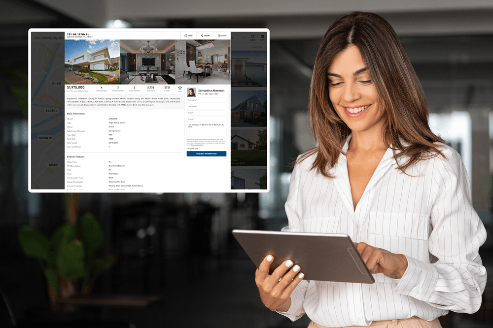 A smiling woman in a white pinstriped blouse stands in a modern office, holding a tablet that shows an idx real estate website showing property photos, pricing details, and an agent’s profile.